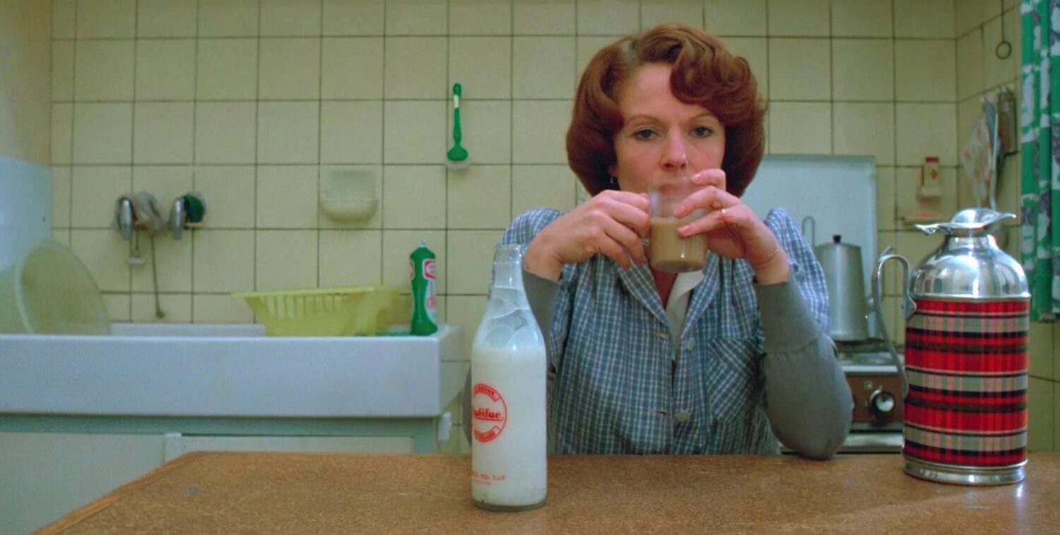 Bilde fra filmen Jeanne Dielman, 23, Quai du Commerce, 1080 Bruxelles - kvinne sitter ved kjøkkenbord med en kopp kaffe